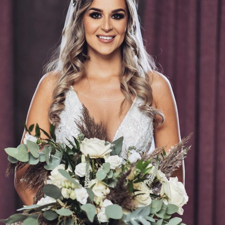 Smiling Bride Holding a Large Bouquet of White Flowers